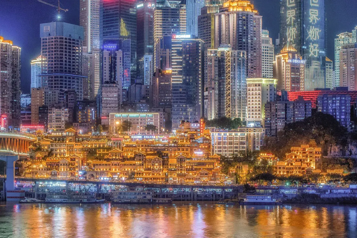 Hongyadong's stacked stilt houses glowing at night above the Jialing River in Chongqing