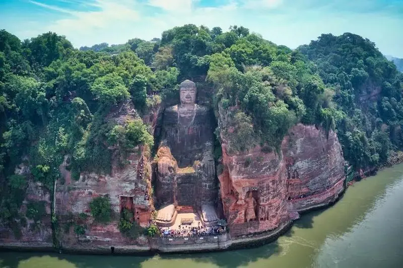 The Leshan Giant Buddha carved into the red cliff above the river, seen from the water