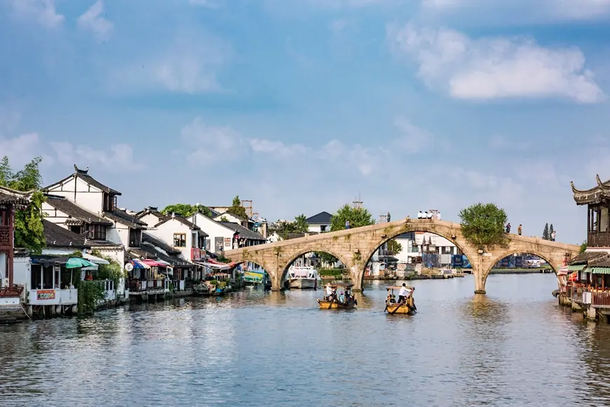 Fangsheng Bridge over the canal in Zhujiajiao water town — tour boats passing under its arches between white-walled houses