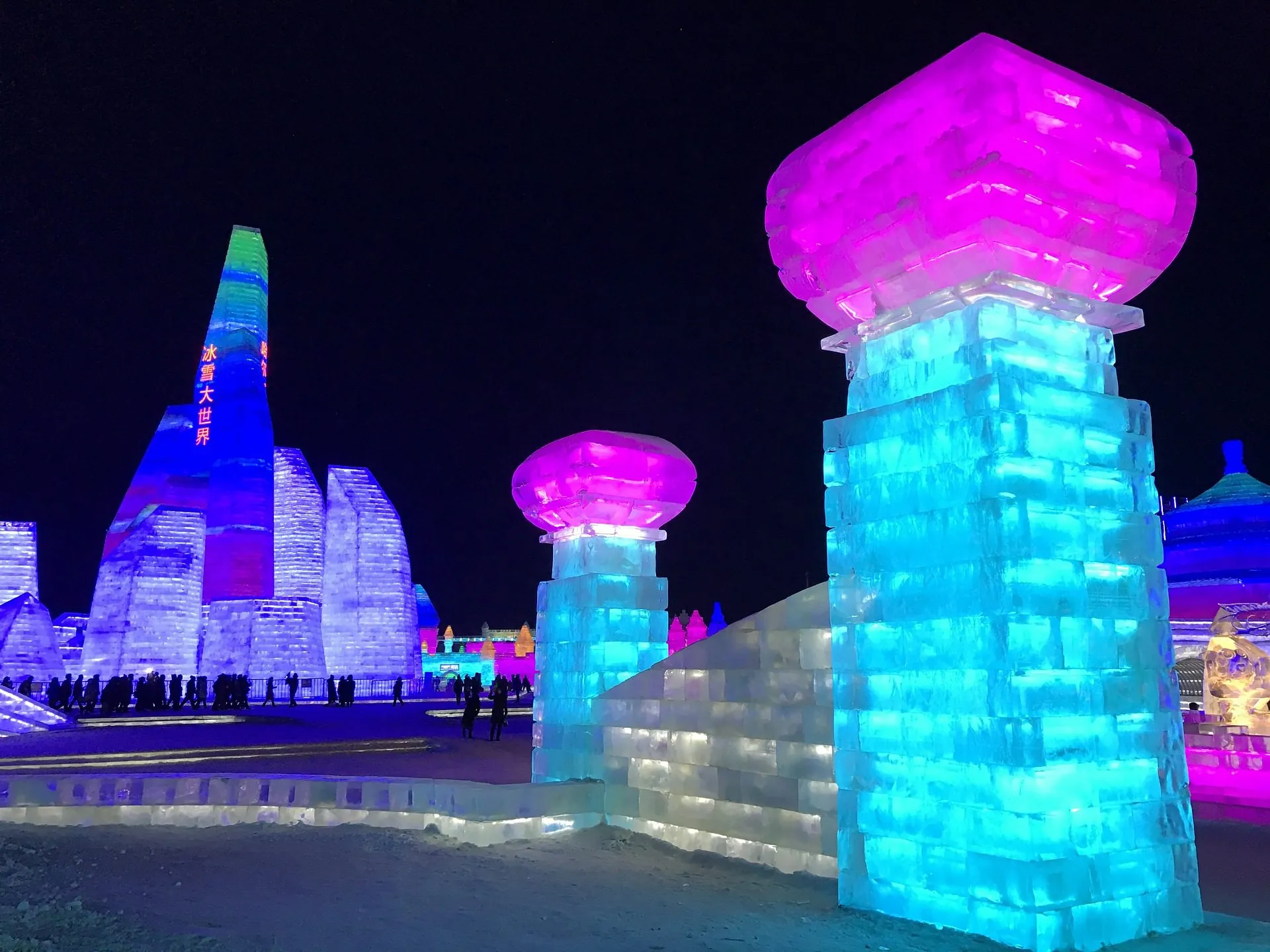 Towering ice sculptures lit in blue and pink at night at Harbin's Ice and Snow World