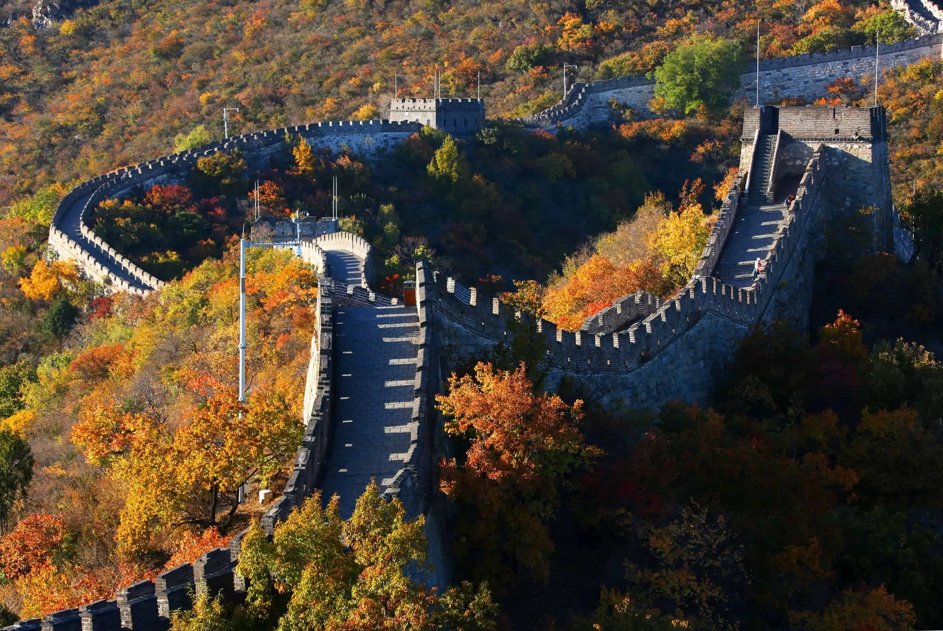The Great Wall at Mutianyu winding through hills covered in red and orange autumn leaves