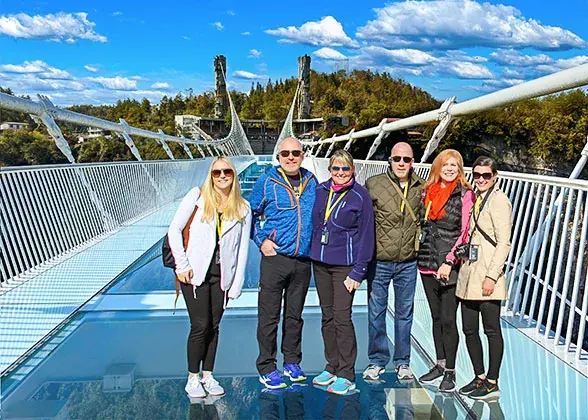 Travellers with their guide standing on the glass bridge over Zhangjiajie Grand Canyon