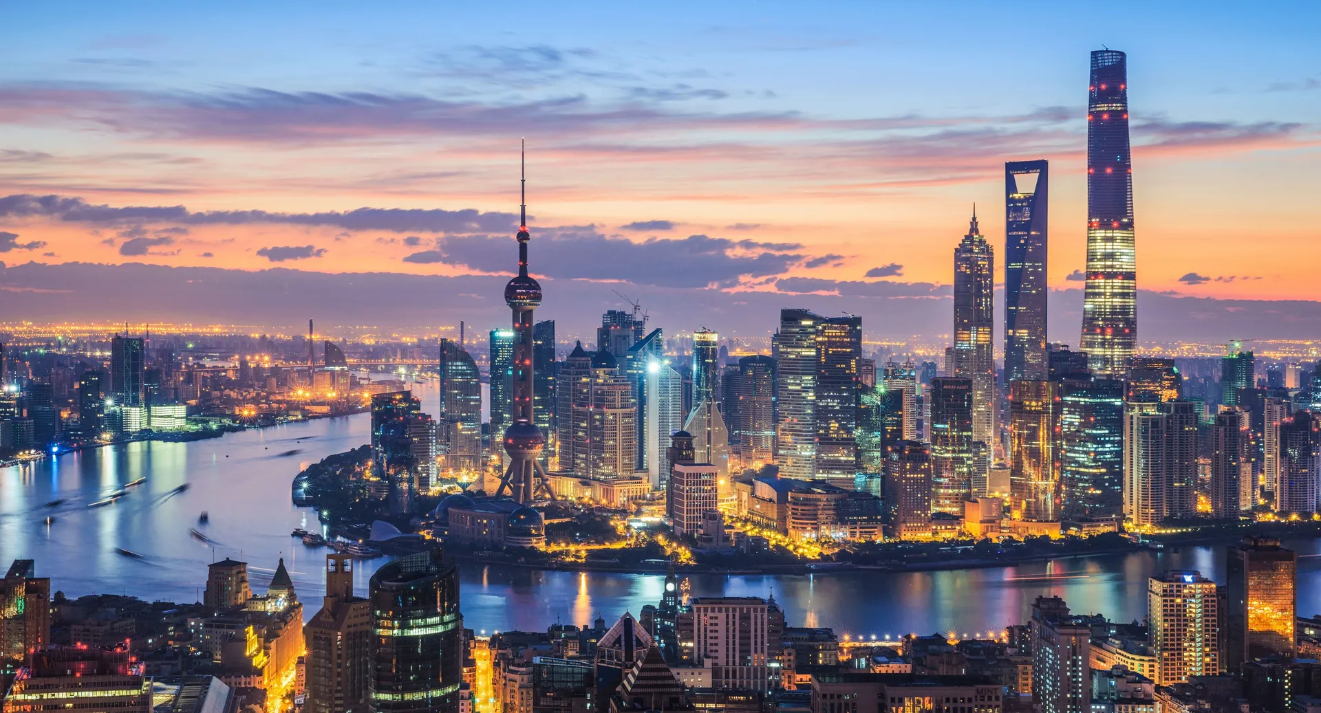 Shanghai from above at dusk — the Huangpu River bend, the Oriental Pearl Tower and Shanghai Tower